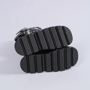 Nahaufnahme schwarzer Punk-Stiefel mit dicken Profilsohlen und silbernen Nietschnallen.