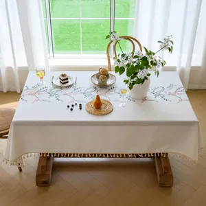 Elegant embroidered floral linen tablecloth with tassels shown in a sunny dining room setting