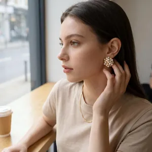 Model wearing vintage pearl sun flower stud earrings in a soft natural light cafe.