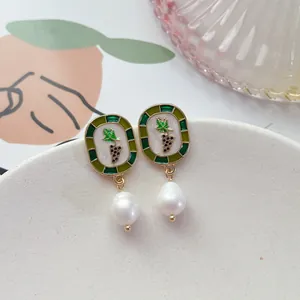 Détail de boucles d'oreilles vintage en émail avec élégante perle baroque pendante