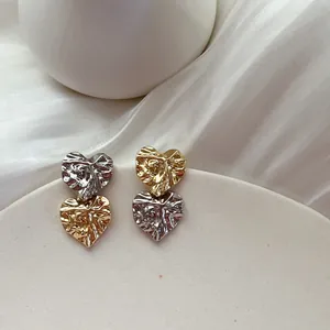 Detailed macro view of elegant heart-shaped earrings featuring a unique wrinkled metal texture