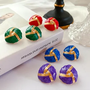 Detail view of vintage enamel stud earrings with golden knot design and marble texture.