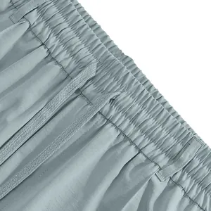 Detail view of men's casual pants with elastic waistband and drawstring in light blue.