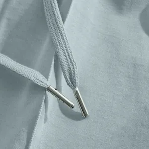 Detailed close-up of premium metal drawstring tips on light blue men's casual trousers