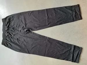 Detailed view of black men's casual drawstring trousers laid flat on grey floor