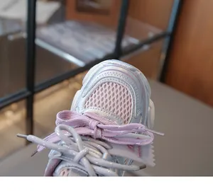 Gros plan de baskets respirantes pour enfants en argent et rose avec lacets détaillés