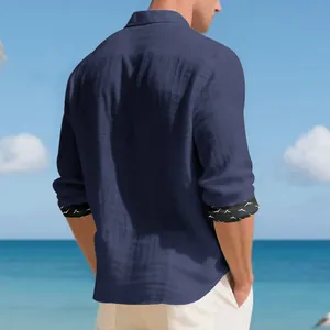 Detailed back view of a navy blue long-sleeve linen shirt for men featuring a beach background