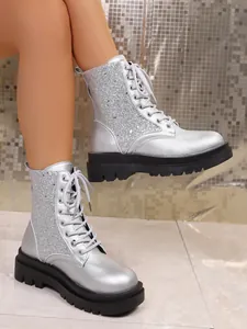 Detailed side view of silver sequin lace-up Martin boots with chunky black platform soles