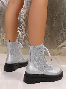 Detailed view of women's silver glitter platform combat boots with white lace-up design.