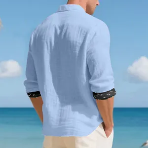 Detail back view of light blue linen men's shirt with bird print cuffs on beach