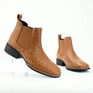 Detailed view of men's brown ostrich texture Chelsea boots with chunky heels on white.