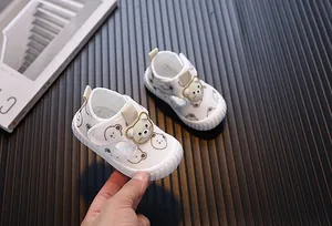Primer plano de zapatos para caminar para bebé con diseño de oso y malla blanca suave.