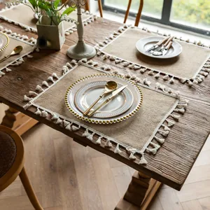 Rustic rectangular jute placemat with white tassels on a vintage wooden table detail