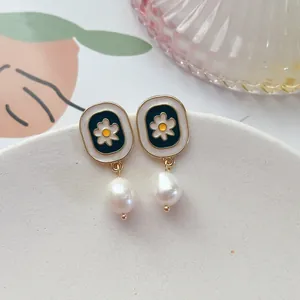 Détail de boucles d'oreilles rétro avec marguerite en émail et perle baroque chic