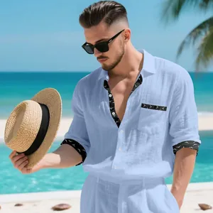 Detailed shot of men's light blue linen shirt with black patterned cuffs in a beach setting