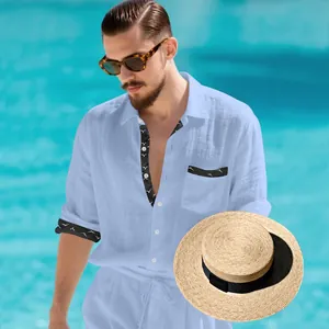 Detail view of men's light blue linen shirt with patterned trim and straw hat