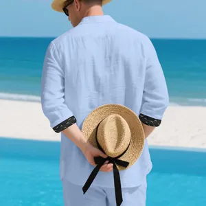 Back view of men's light blue linen leisure shirt with patterned cuffs on a sunny beach