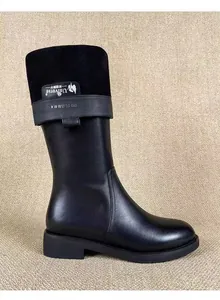 Detailed view of stylish black knee-high leather boots with suede top and buckle strap