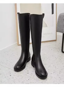 Detailed view of elegant black knee-high leather boots with inner zipper and round toe