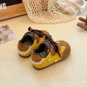 Detailed view of yellow toddler girl sneakers with flower embroidery and lace accents