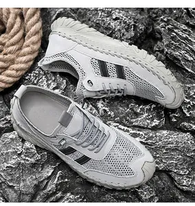 Macro view of men's breathable grey mesh outdoor walking shoes on a natural rocky background
