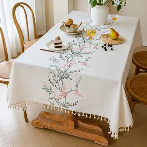 Detailed view of cream linen tablecloth with pink floral embroidery and tassels