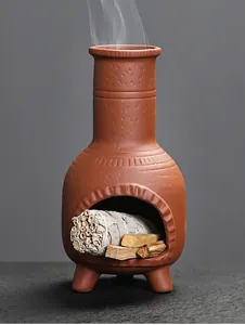 Detailed view of a terracotta chimenea incense burner with burning sage and palo santo.