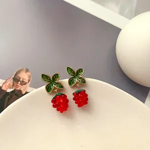 Nahaufnahme von Vintage-Beeren-Emaille-Ohrringen mit roten Perlen und grünen Blättern