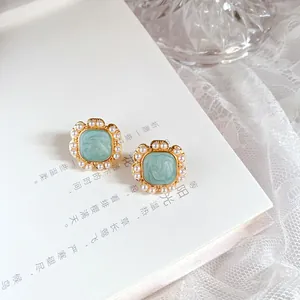 Detail view of retro French earrings with mint green enamel and pearls