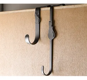 Detail view of creative black cat metal S-shaped over-the-door hooks on wooden surface.