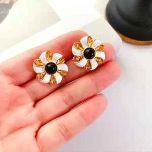 Vue macro détaillée de boucles d'oreilles fleurs en émail vintage blanc et doré
