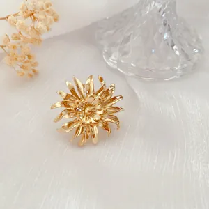 Nahaufnahme einer eleganten goldenen Chrysanthemen-Brosche mit barockem Blumendesign-Detail