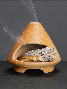 Macro view of a ceramic aromatherapy burner with burning sage and palo santo wood