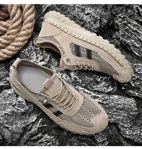 Macro view of men's khaki breathable mesh outdoor shoes on dark rugged rocks.