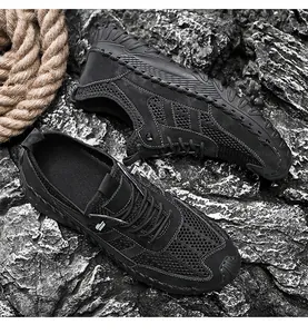 Overhead macro view of breathable black mesh men's outdoor casual shoes on rocky terrain