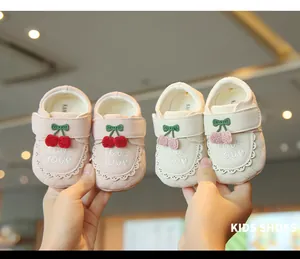 Gros plan de chaussures de princesse pour bébé à semelle souple avec broderie cerise