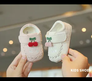 Gros plan de chaussures de marche pour bébé roses et beige avec cerise et broderie