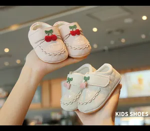 Gros plan de chaussures de marche pour bébé roses et crème avec broderie de cerises