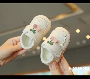 Gros plan de chaussures de marche bébé crème avec décor cerise en peluche et broderie.