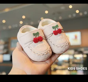 Gros plan de chaussures de marche roses pour bébé avec broderie cerise et bords festonnés