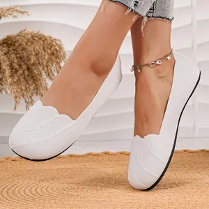 Close-up of white breathable knitted flat shoes with decorative wavy edge detail