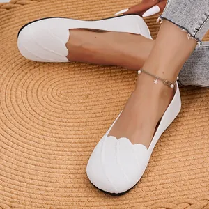 Detailed view of white breathable flyknit flat shoes with scalloped edges on straw mat