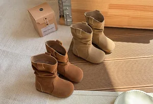 Gros plan sur des bottes plissées en daim pour filles aux tons marron rétro