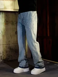 Detail of men's loose light blue jeans with pearl embellishments and straight-leg fit