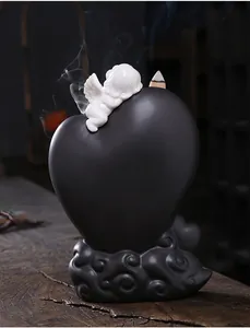 Detailed macro view of black heart backflow incense burner with white ceramic cupid angel