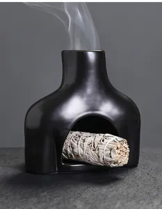 Detailansicht eines schwarzen Keramik-Räuchergefäßes in Torso-Form mit weißem Salbei