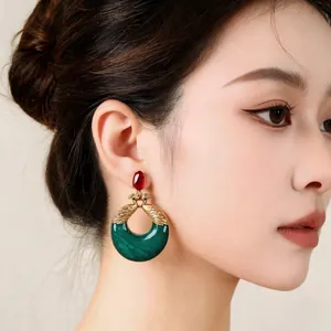 Detalle de pendientes vintage de pavo real en resina con colgante verde