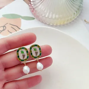 Vue détaillée de boucles d'oreilles vintage en émail raisin et perles baroques.