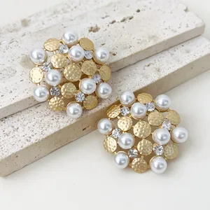 Close-up of vintage sunflower pearl stud earrings with hammered gold and crystals
