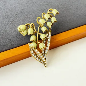 Detailed close-up of a vintage enamel lily of the valley brooch with sparkling rhinestones